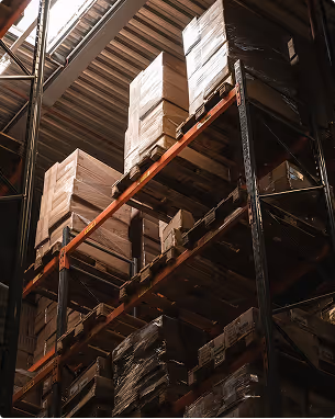 Stacks of cardboard boxes stored on industrial metal shelves in a dimly lit warehouse.