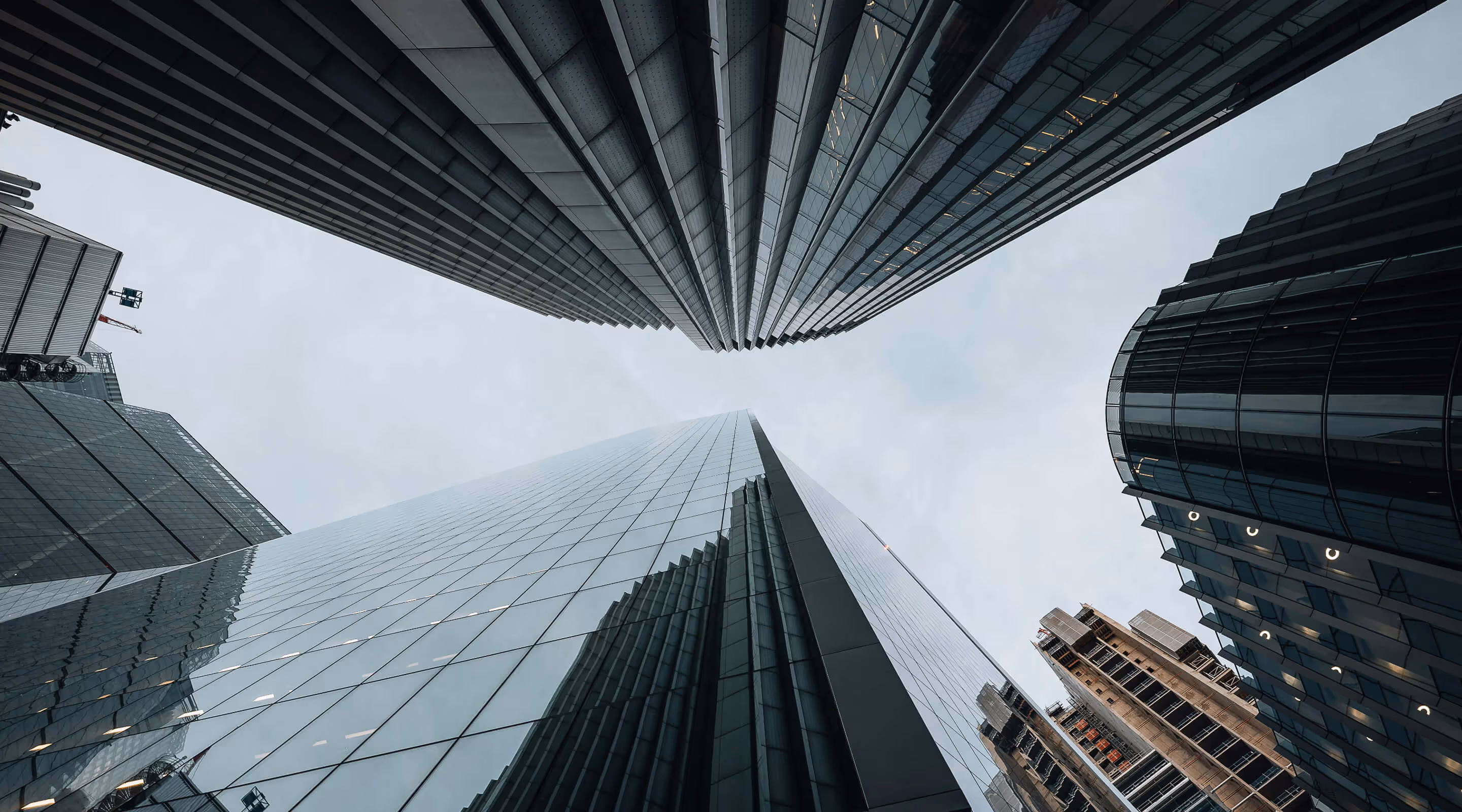 Two men outdoors examining machinery controls on an orange piece of equipment.