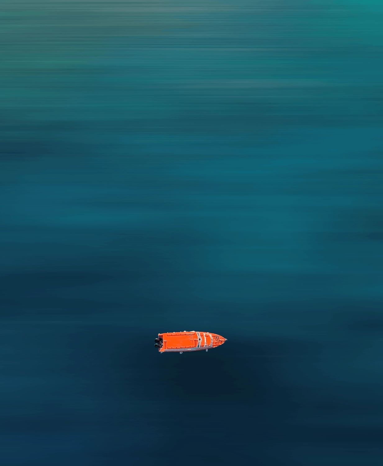 A single bright orange boat floating on calm, deep blue water viewed from above.
Patrick Zilke in Fiji
