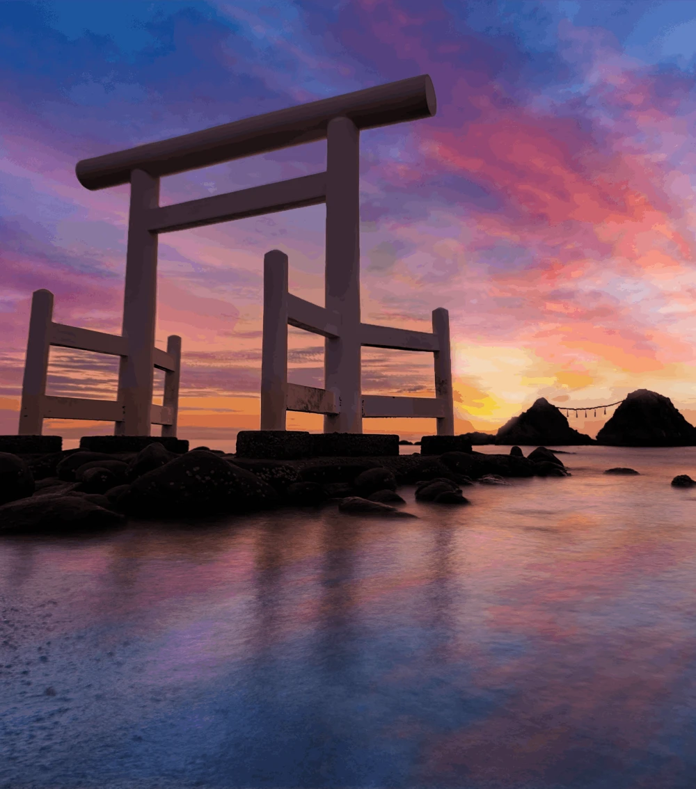 Large torii gate standing in shallow water with rocky shoreline at sunset, colorful sky reflecting on calm sea, with two connected small rocky islands in the background.
Patrick Zilke in Japan