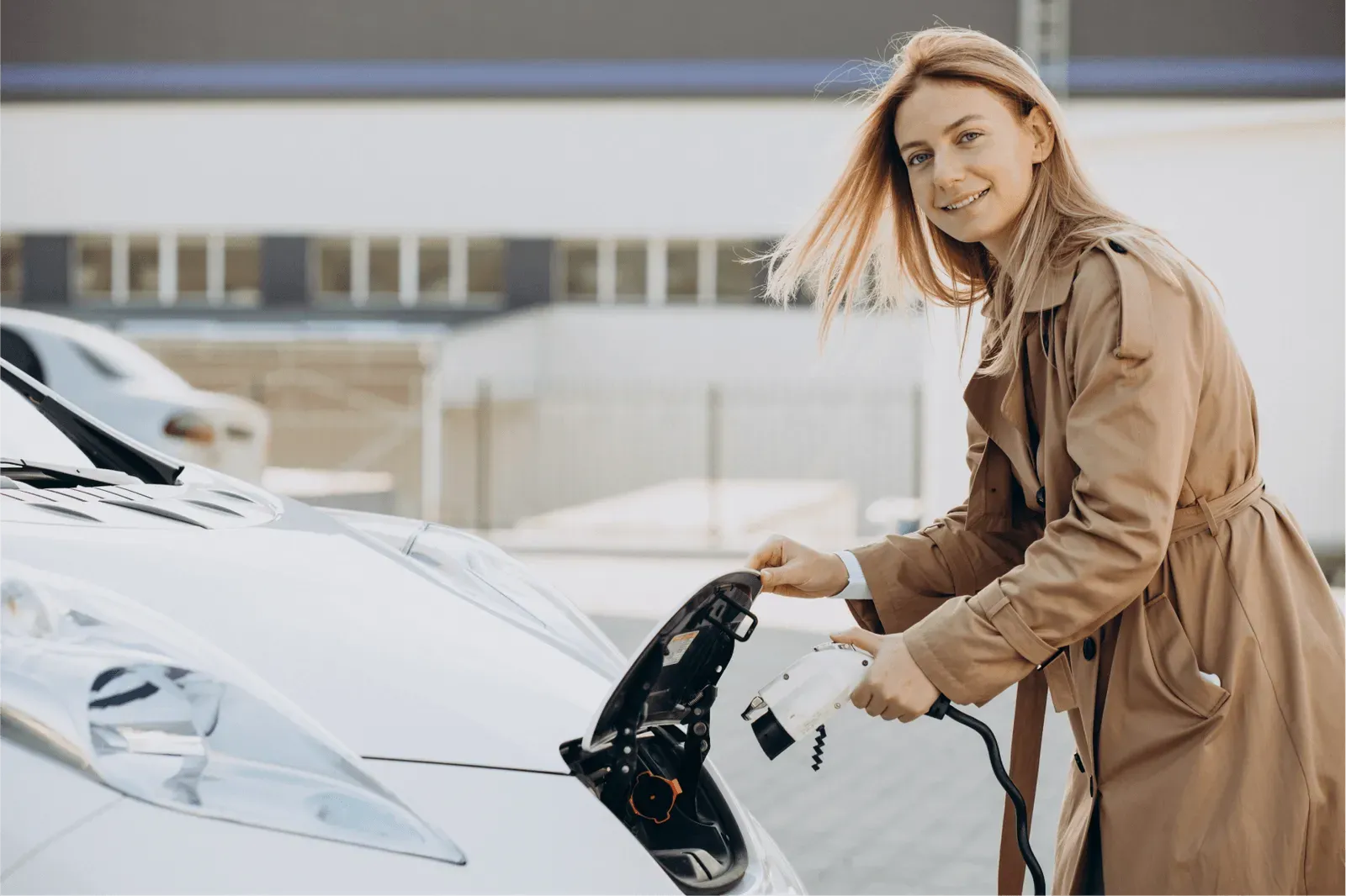 Woman looking at the camera while charging an EV car.