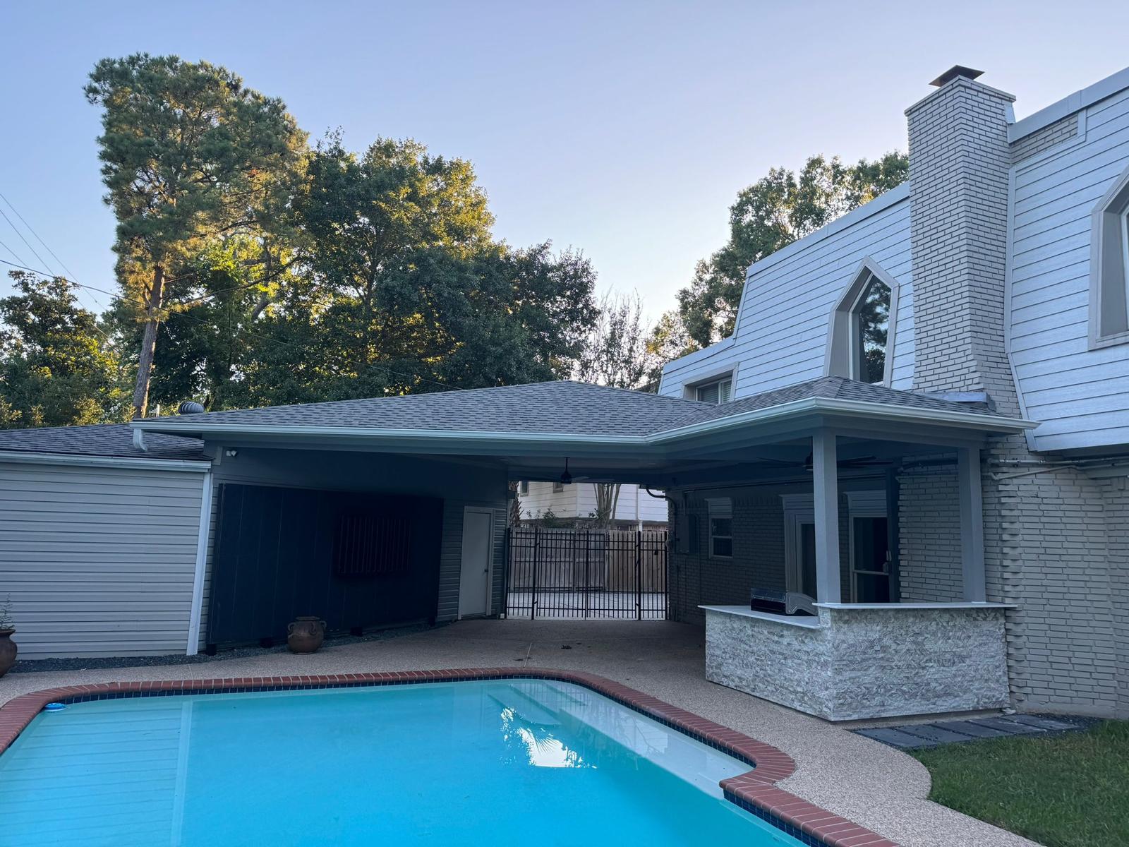 Covered extension built off the back of a Houston home beside the pool, with a new roofline tied into the house.
