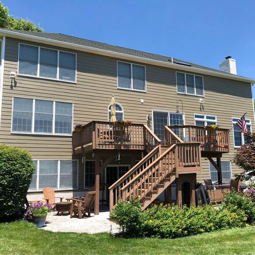 White mobile home with green shutters, window air conditioners, and stone-patterned skirting on a grassy lawn.