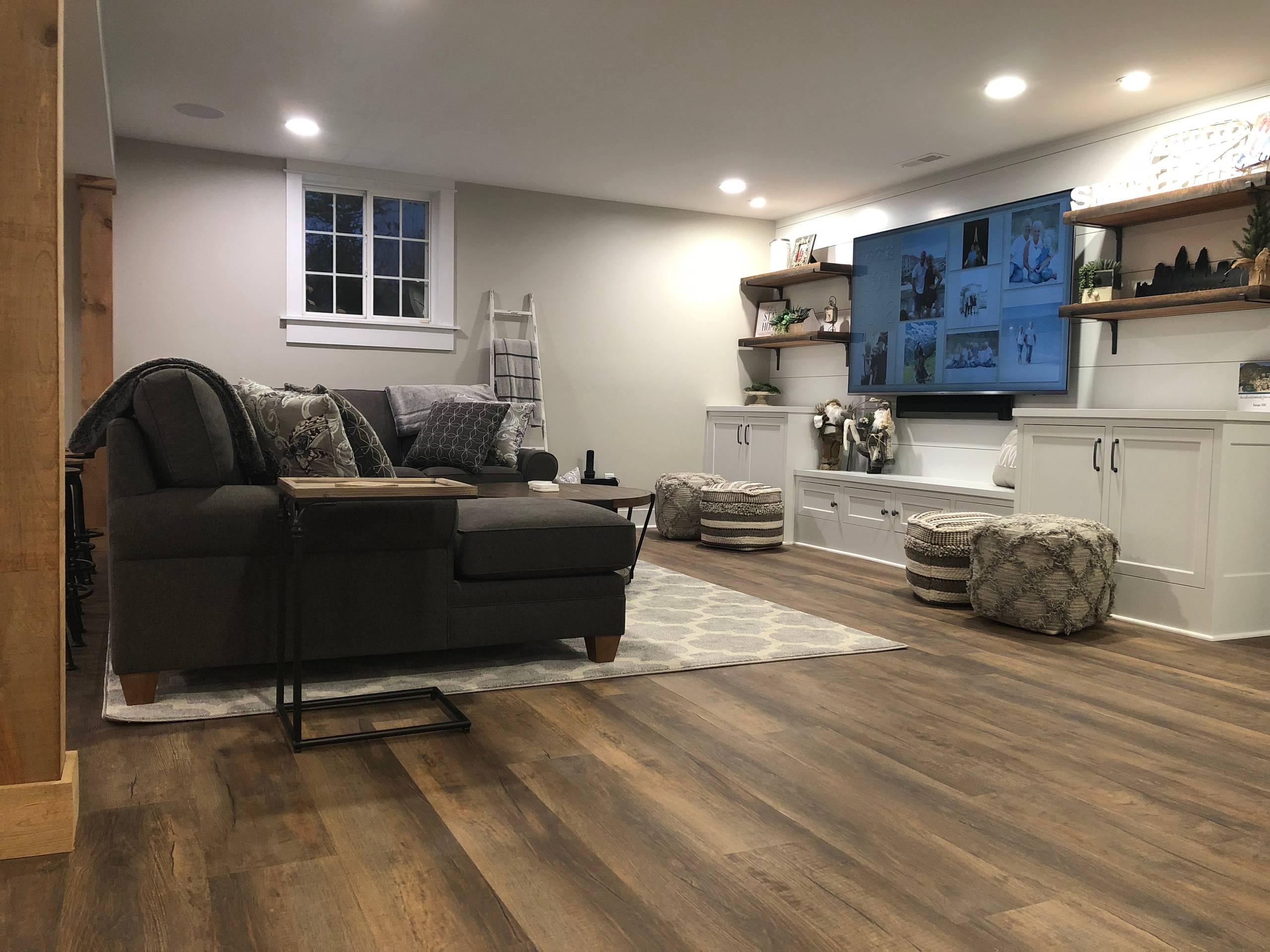 Remodeled living room with wood-look flooring, built-in shelving and a mounted TV.