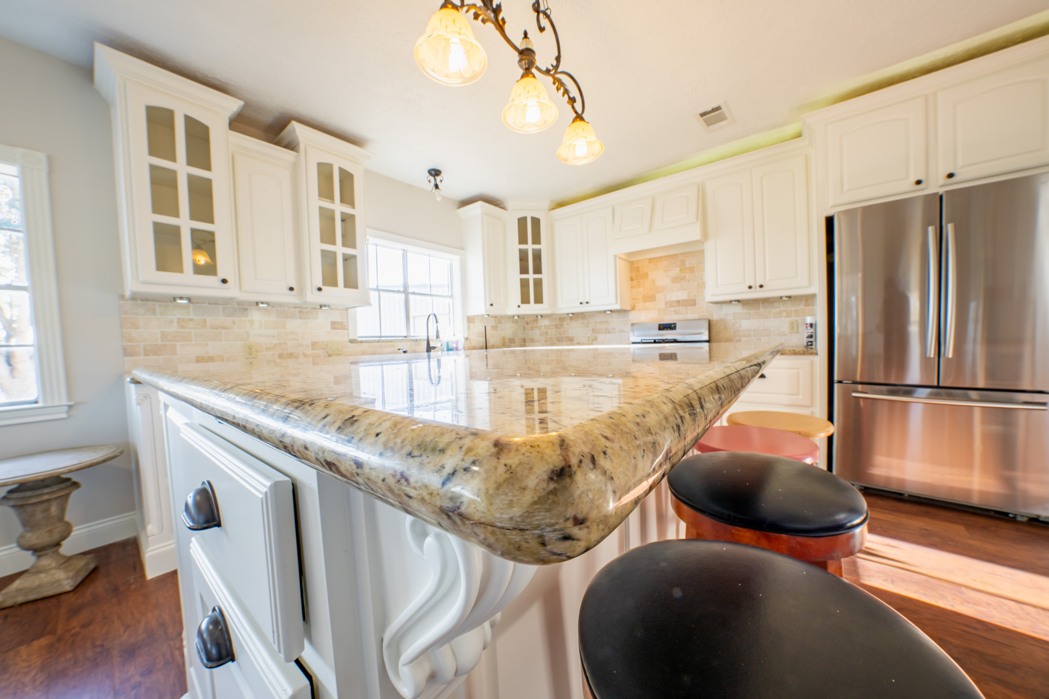 Kitchen with white cabinets, a granite-topped island with bar seating, and stainless steel appliances.