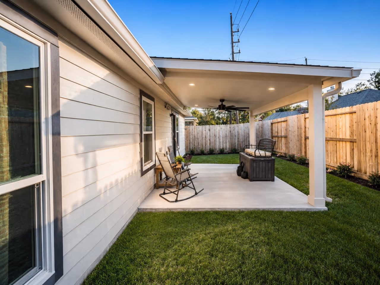 Completed attached patio cover in Houston featuring a seamless painted ceiling, integrated recessed LED lighting, and an outdoor ceiling fan for comfortable year-round use.