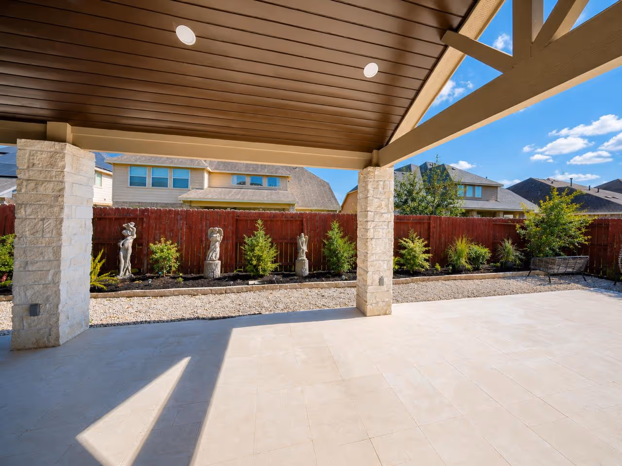 Luxury custom patio cover build in the Houston area highlighting a premium dark wood paneled ceiling, modern recessed lighting, structural beams, and a high-end masonry stone column.