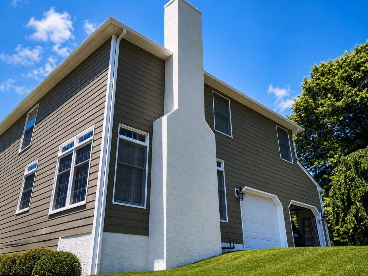 Completed exterior remodeling project in Houston displaying expertly installed olive-green horizontal lap siding paired seamlessly with a painted stucco foundation and chimney.