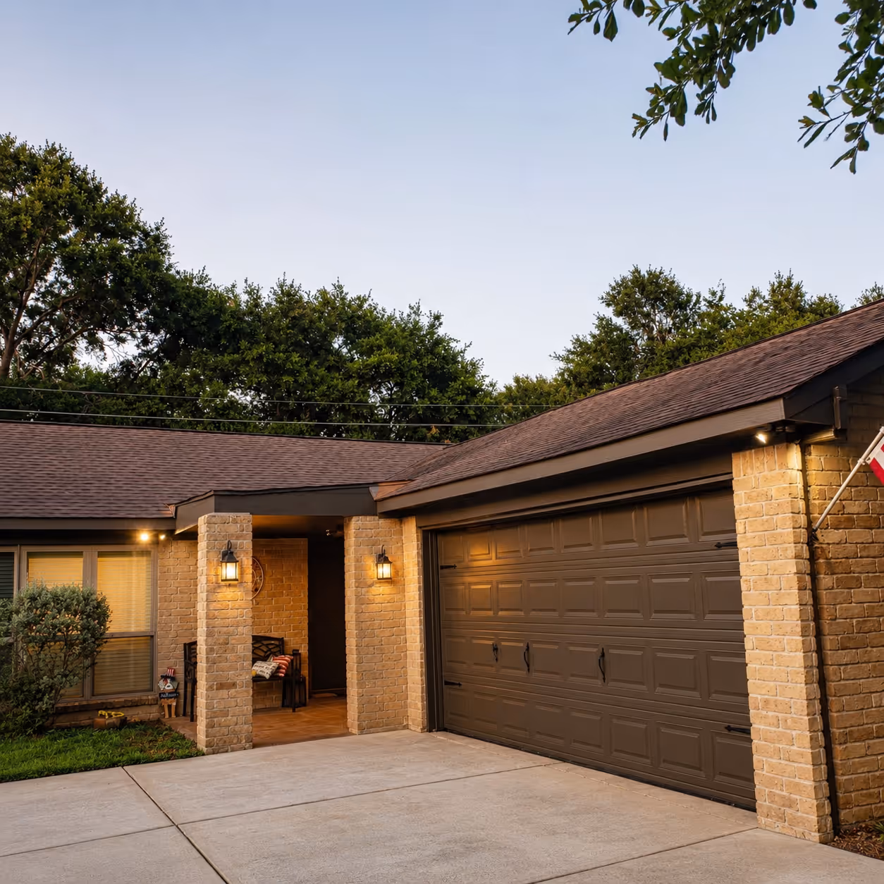 Front exterior of a Houston brick home with a covered porch and brown garage door, highlighting an exterior remodeling project with updated roof trim.