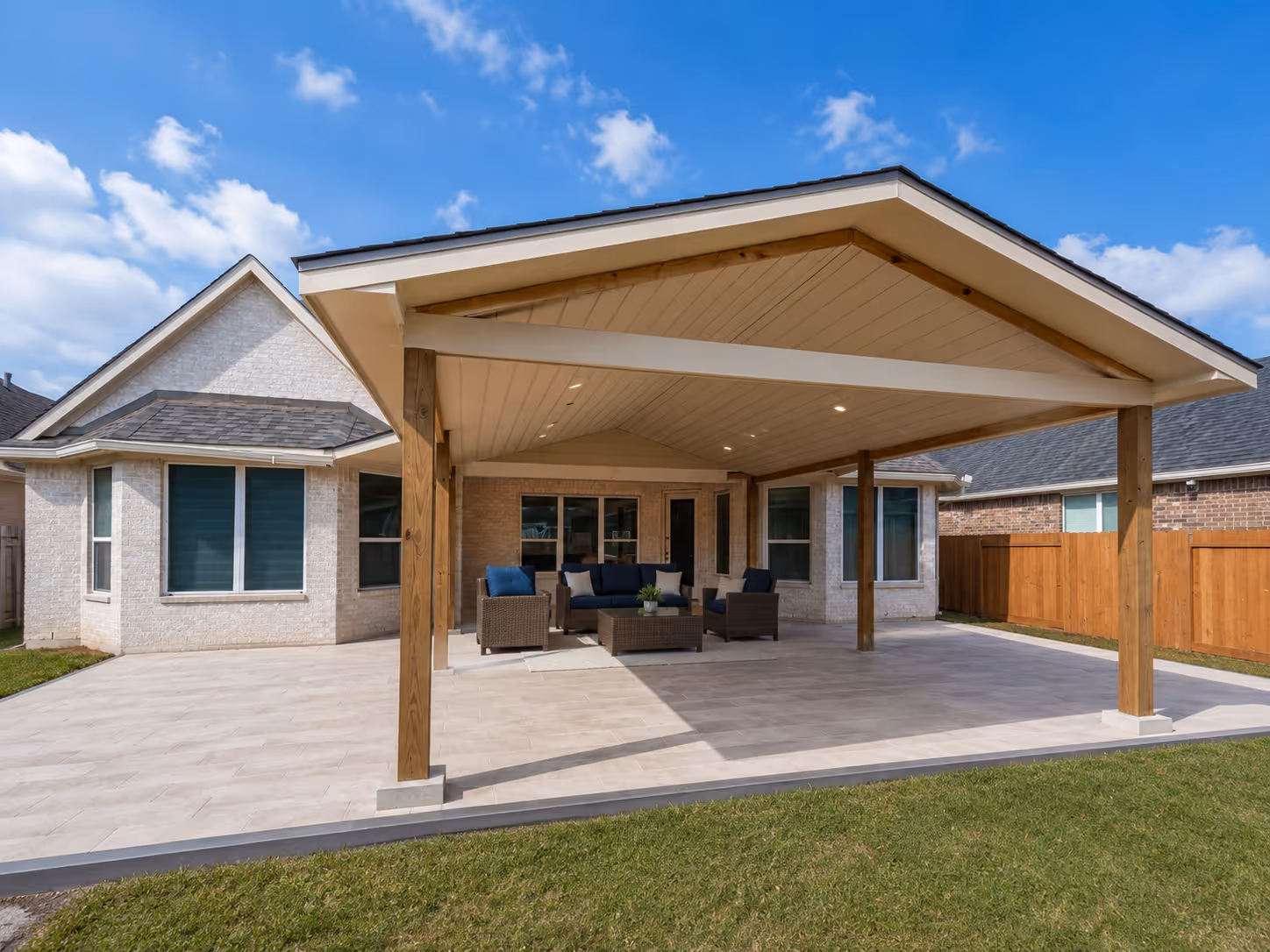 Custom gabled patio cover installation in Houston, showcasing a seamless roofline tie-in, sturdy wooden framing, and a spacious concrete foundation for outdoor living.