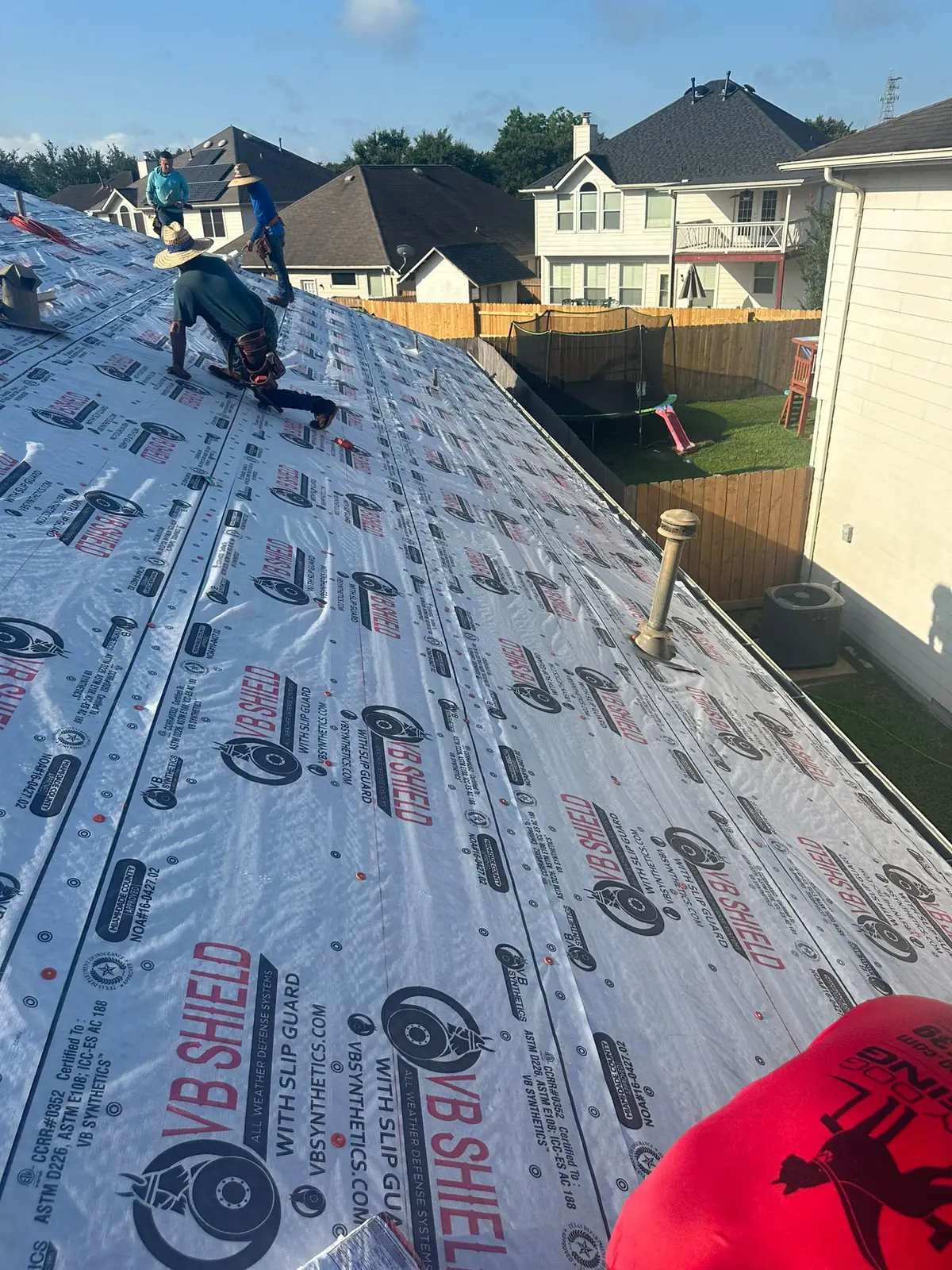 Installing synthetic roofing underlayment during a residential roof replacement in Houston
