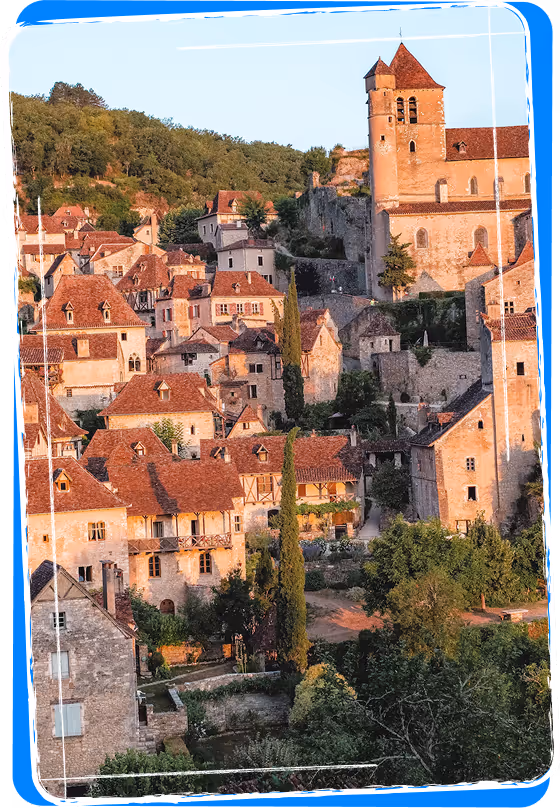 Historic hillside village with stone houses and red-tiled roofs surrounded by trees, featuring a tall church tower.