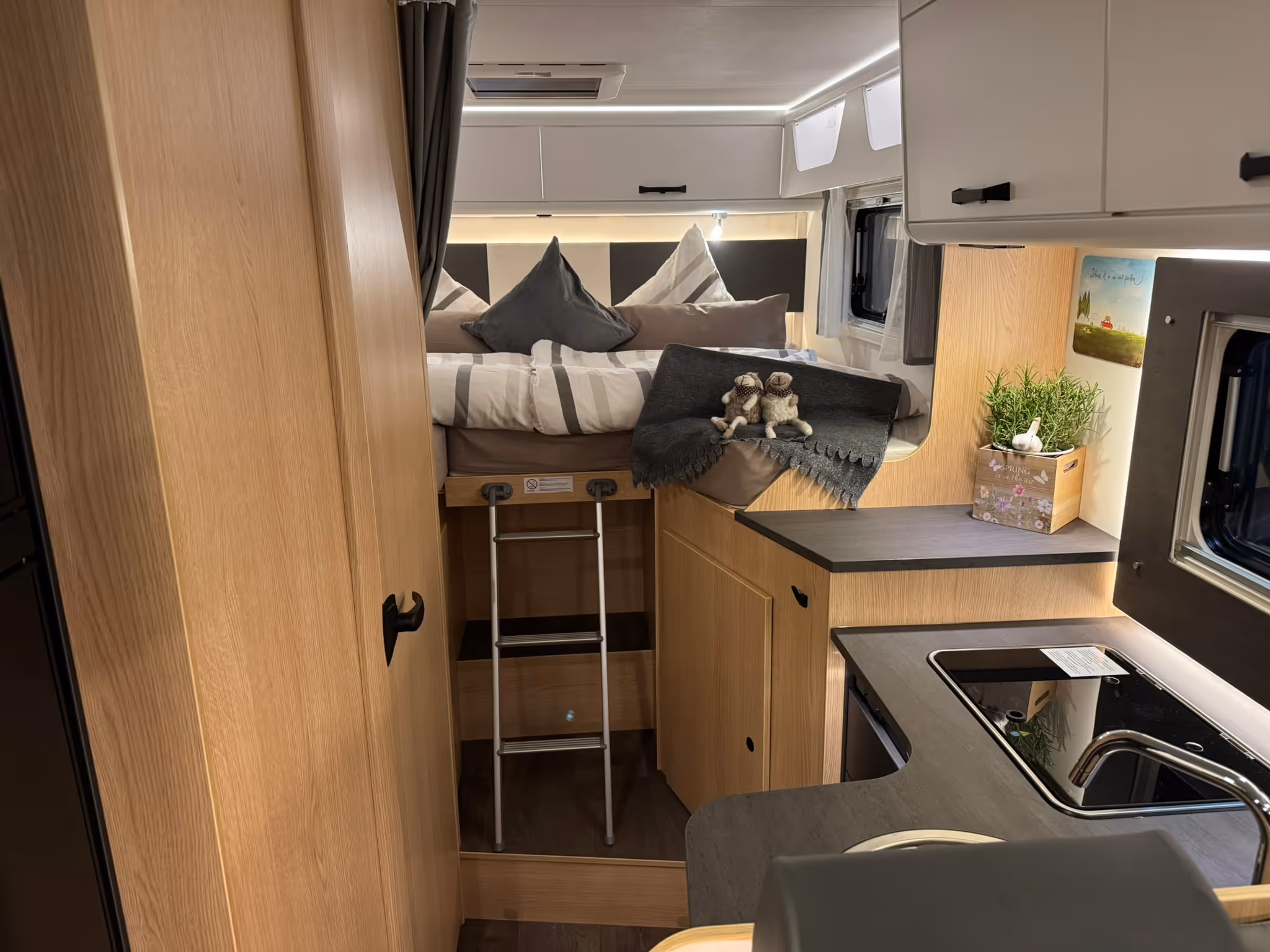 Kompaktes Badezimmer mit weißer Toilette, quadratischem Waschbecken auf schwarzem Unterschrank und Holzabdeckung im Duschbereich.