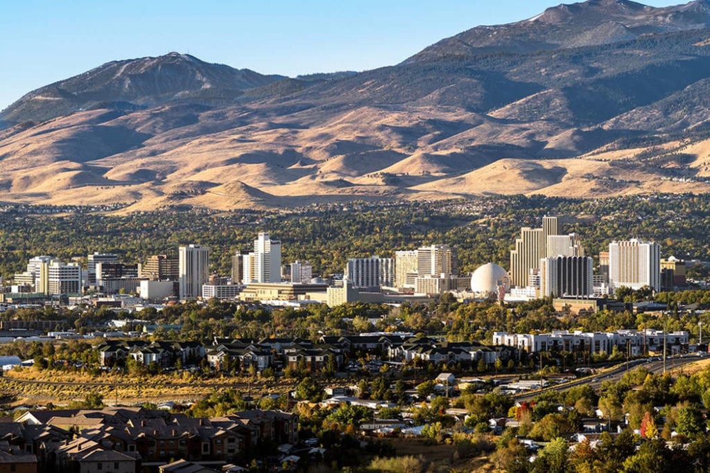 Residential houses and tall buildings in front of large, sandy mountains