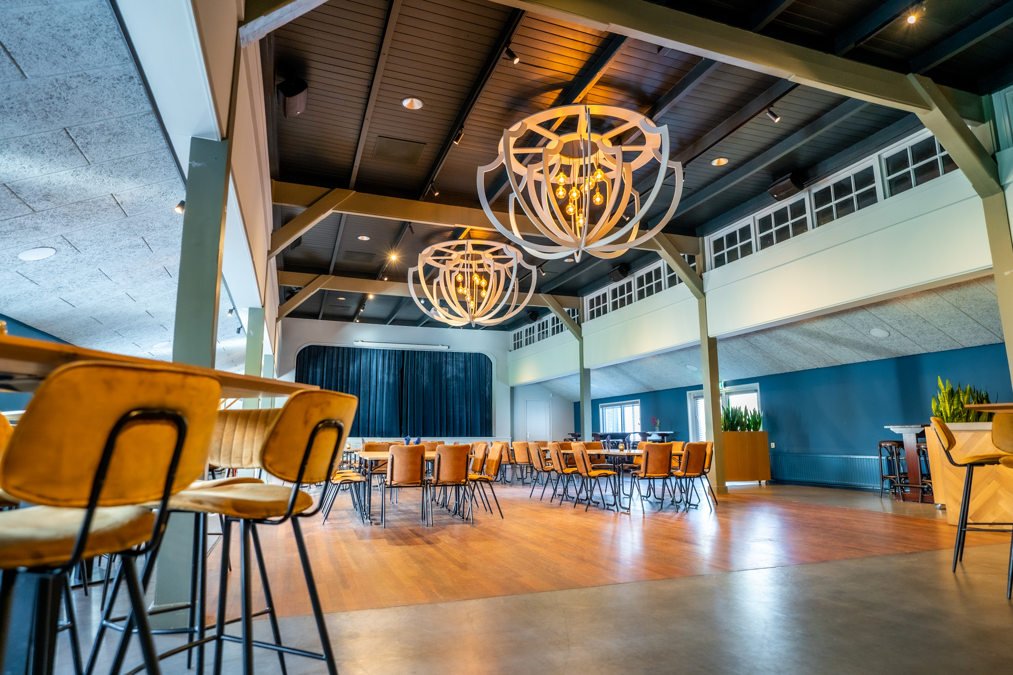 Moderne en ruime eetzaal met gele stoelen, houten vloeren en grote decoratieve hanglampen aan het plafond.