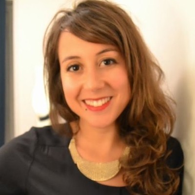 Black and white portrait of a smiling man in a white shirt and dark jacket against a plain background.
