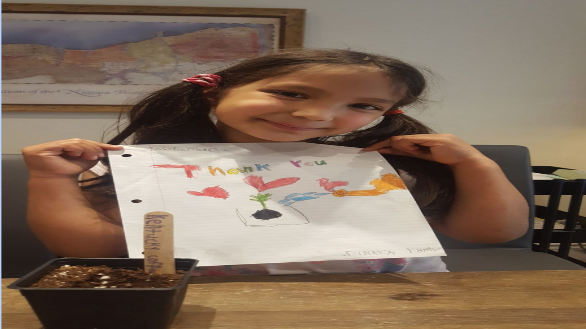 child is holding a thank you drawing