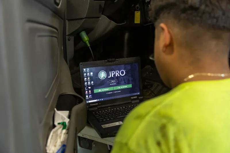 Diagnostics technician using JPRO software to troubleshoot a heavy-duty truck electrical system.