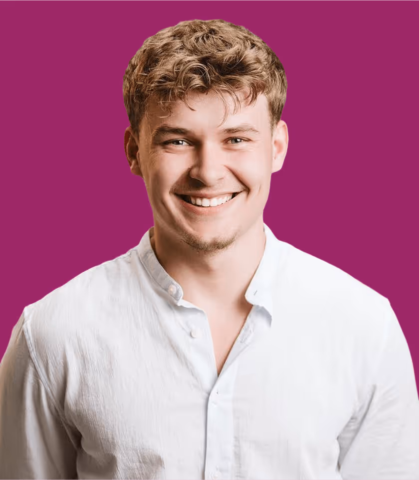 Lächelnder Mann in weißem Hemd vor lila Hintergrund.