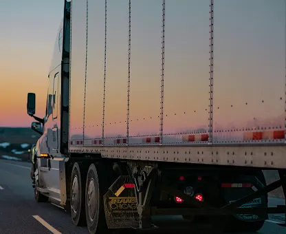 Large semi-truck driving on a highway during sunset with a clear sky.