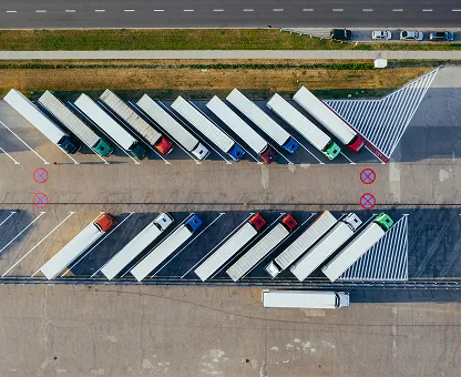 Aerial view of trucks parked diagonally in a lot near a road.
