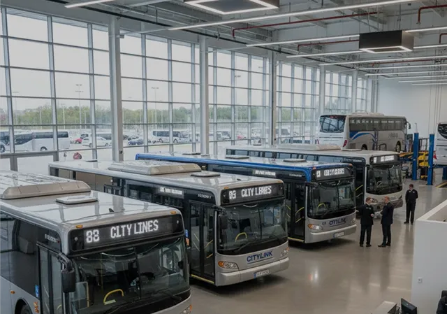 Indoor bus depot with multiple CityLink buses parked in a row and two people standing nearby.