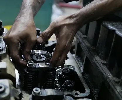 Hands working on mechanical parts of an engine with several valve springs visible.