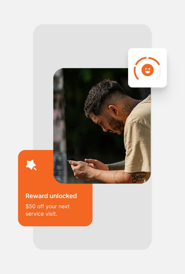 Man with tattoos looking down at a phone, with overlay text 'Reward unlocked $50 off your next service visit.'