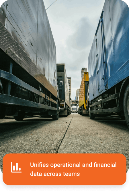 Low-angle view of trucks parked in two rows on a city street under a cloudy sky.