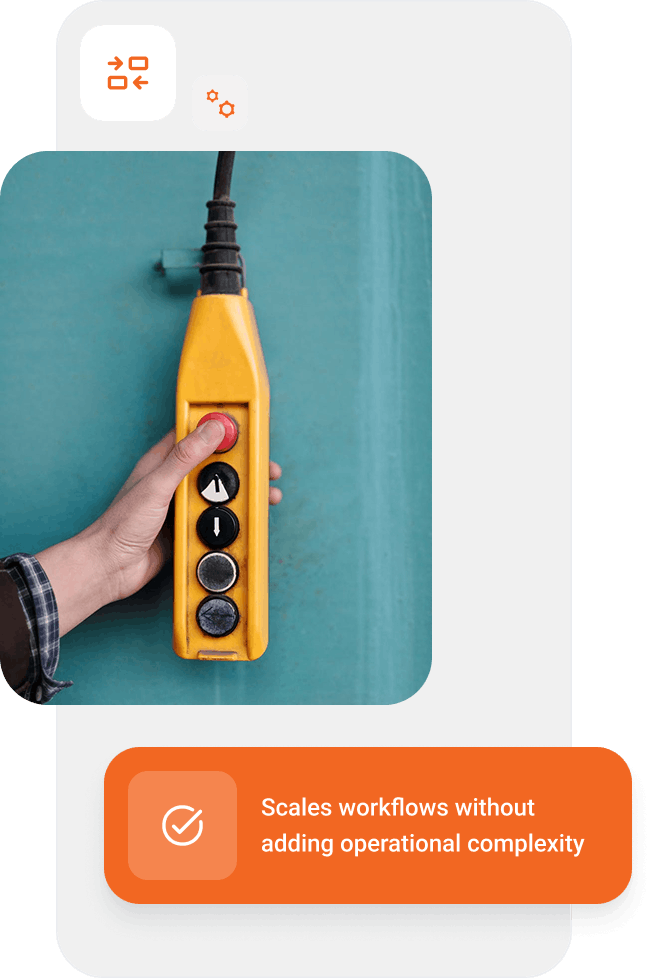 Hand pressing a red button on a yellow industrial control pendant held against a teal background.