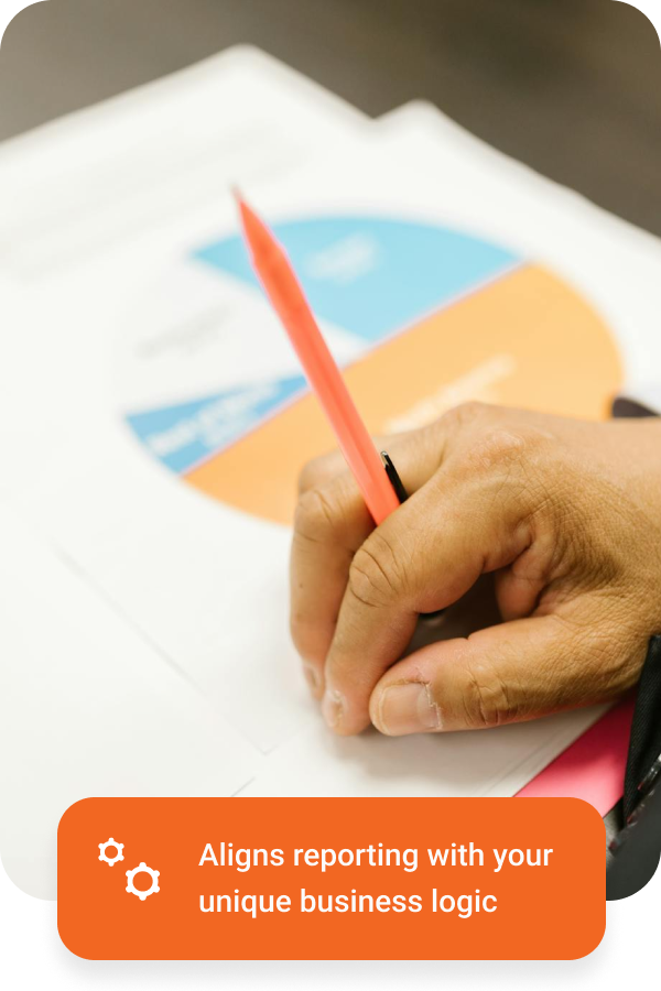 Hand holding a red pen pointing at a pie chart on a printed report.