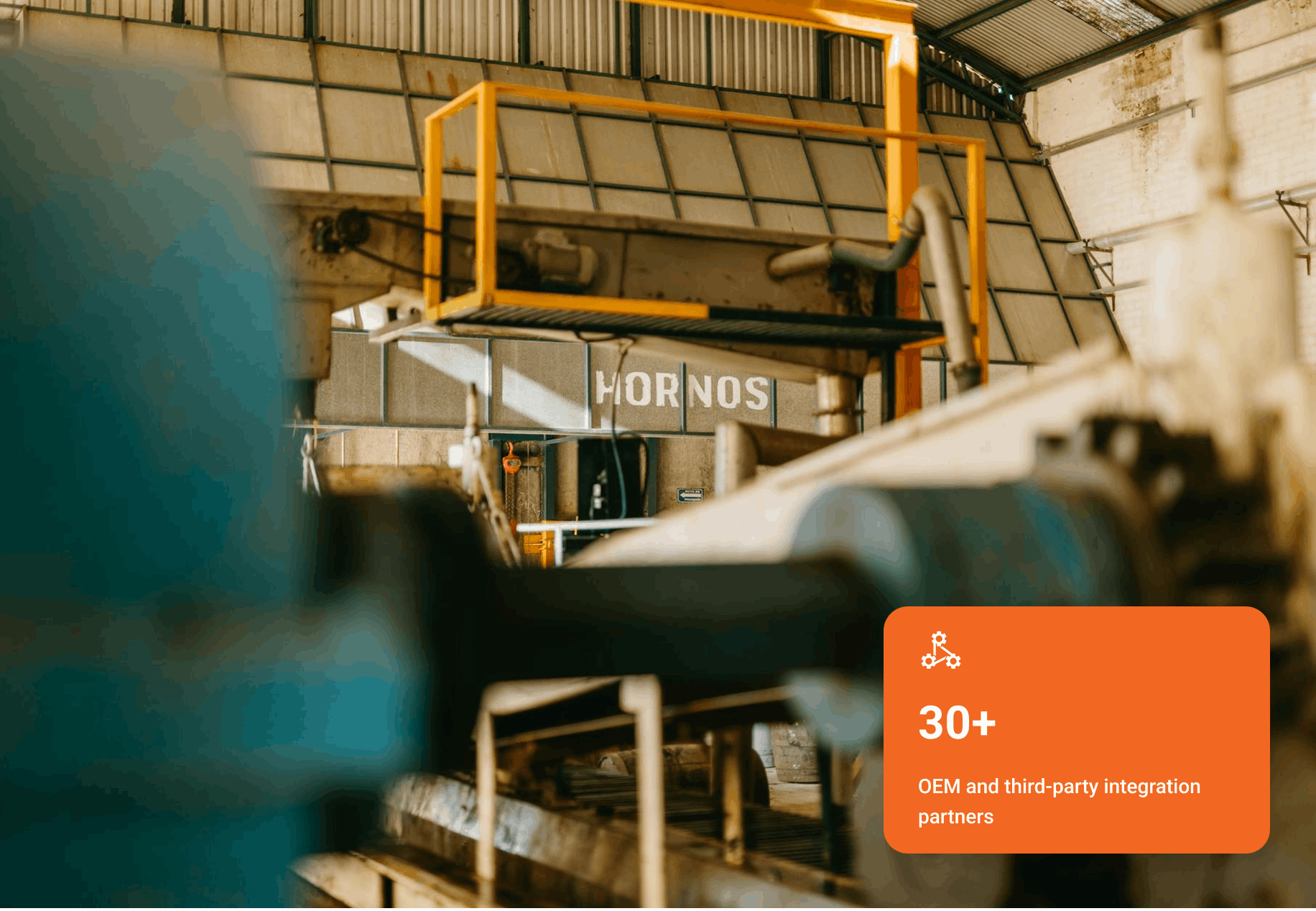 Industrial oven labeled 'HORNOS' inside a factory with blurred machinery parts in foreground.
