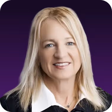 Portrait of a smiling woman with long blonde hair wearing a black top and white collared shirt against a purple background.