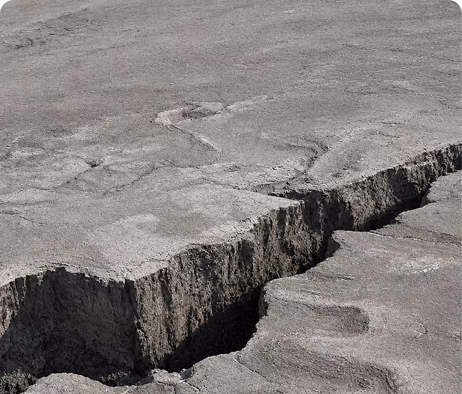 Close-up of a large cracked and dry earth surface with a prominent deep fissure running through it.