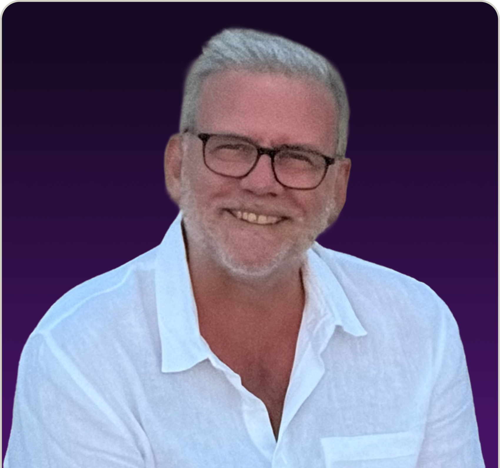 Smiling middle-aged man with short gray hair and beard wearing black glasses and a white shirt against a dark purple background.