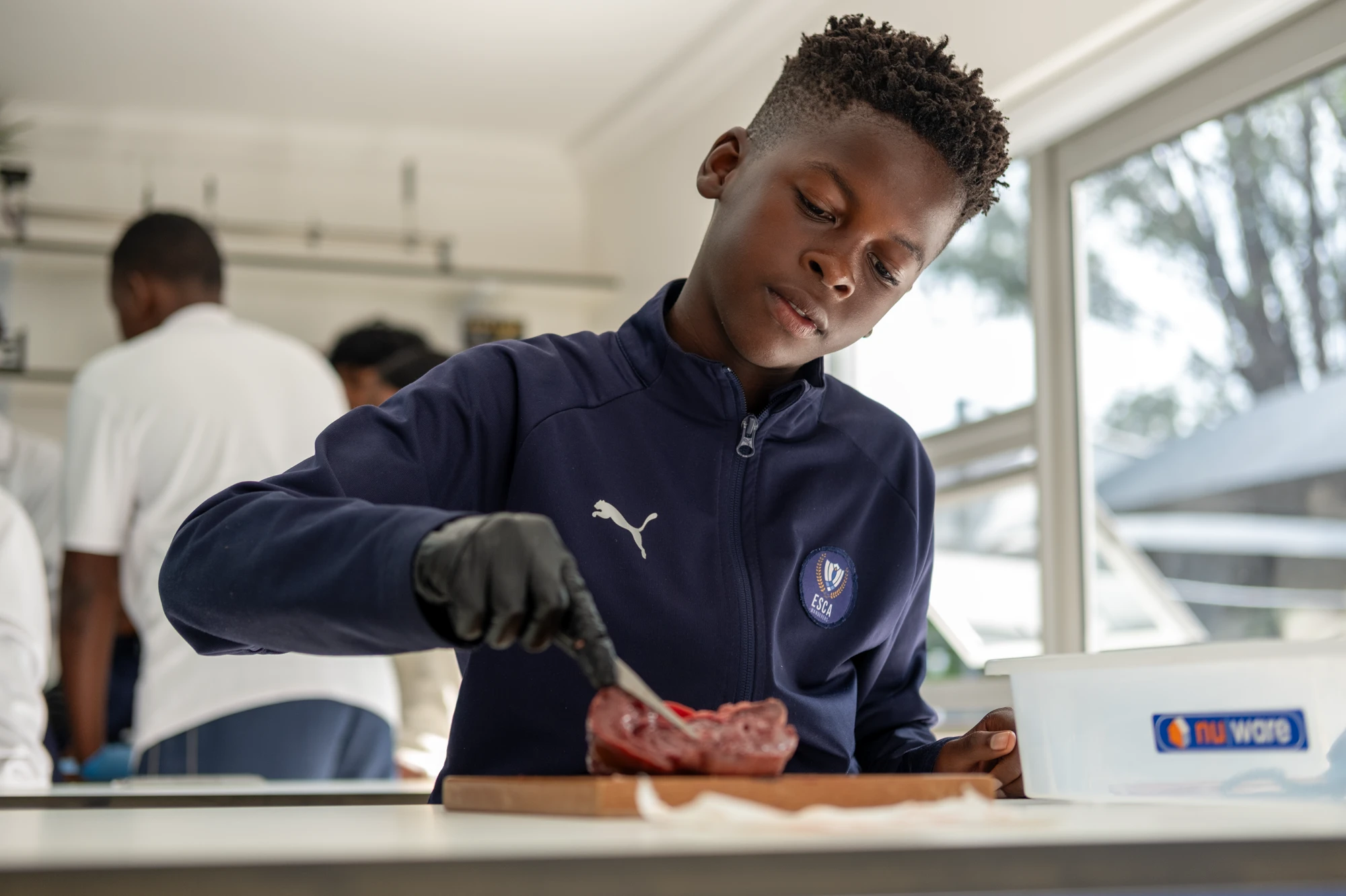 Esca Boy Preparing Meat In Kitchen