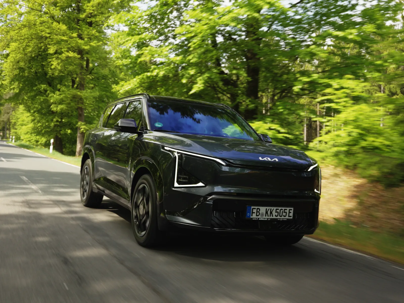 Schwarzer Kia frontal auf der Landstraße im Wald