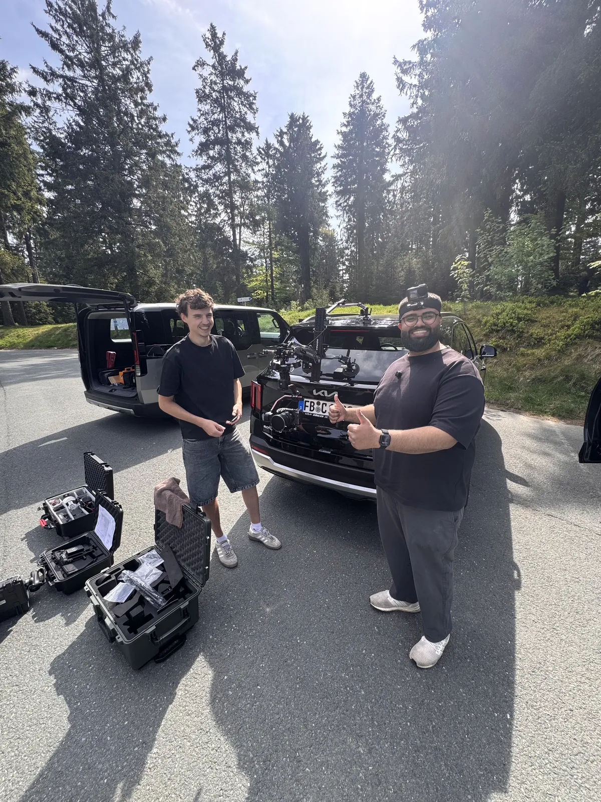 Crew mit Car Rig und Equipmentkoffern am Waldparkplatz