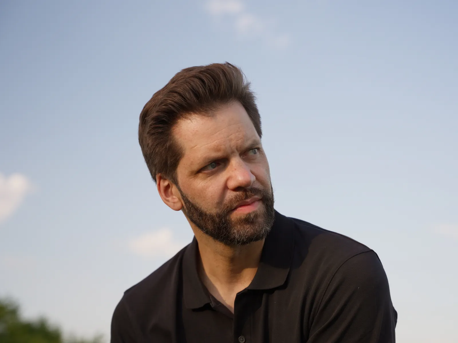 Chris Römhild blickt zur Seite, dahinter blauer Himmel
