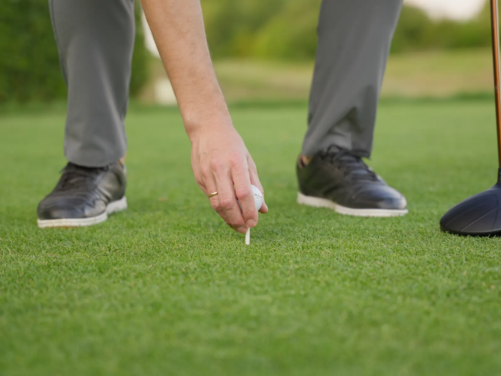 Hand setzt einen Golfball auf das Tee