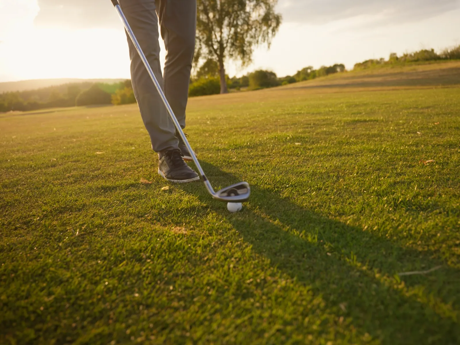 Golfschläger am Ball auf dem Fairway in der Abendsonne