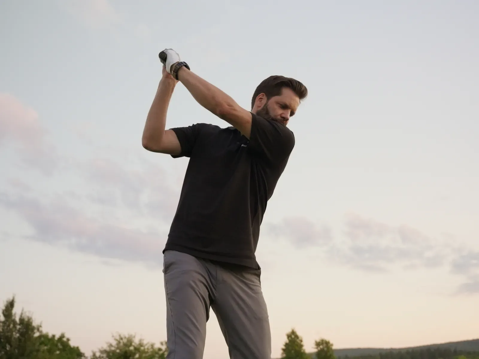 Golfer holt vor dem Abendhimmel zum Schlag aus