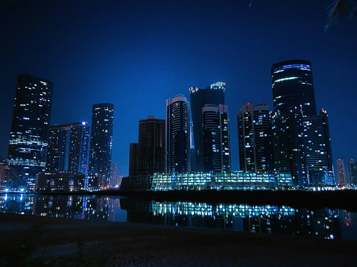 Night view of Al Reem Island skyline with illuminated residential towers reflected in water