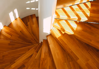 Holztreppe mit Sonnenlicht und Schatten, die ein Muster auf den Stufen erzeugen.