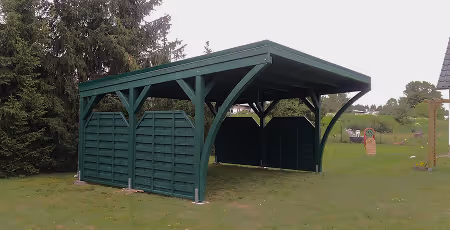 Grünes, offenes Gartenhaus mit Dach und seitlichen Paneelen auf einem Rasen mit Bäumen im Hintergrund.