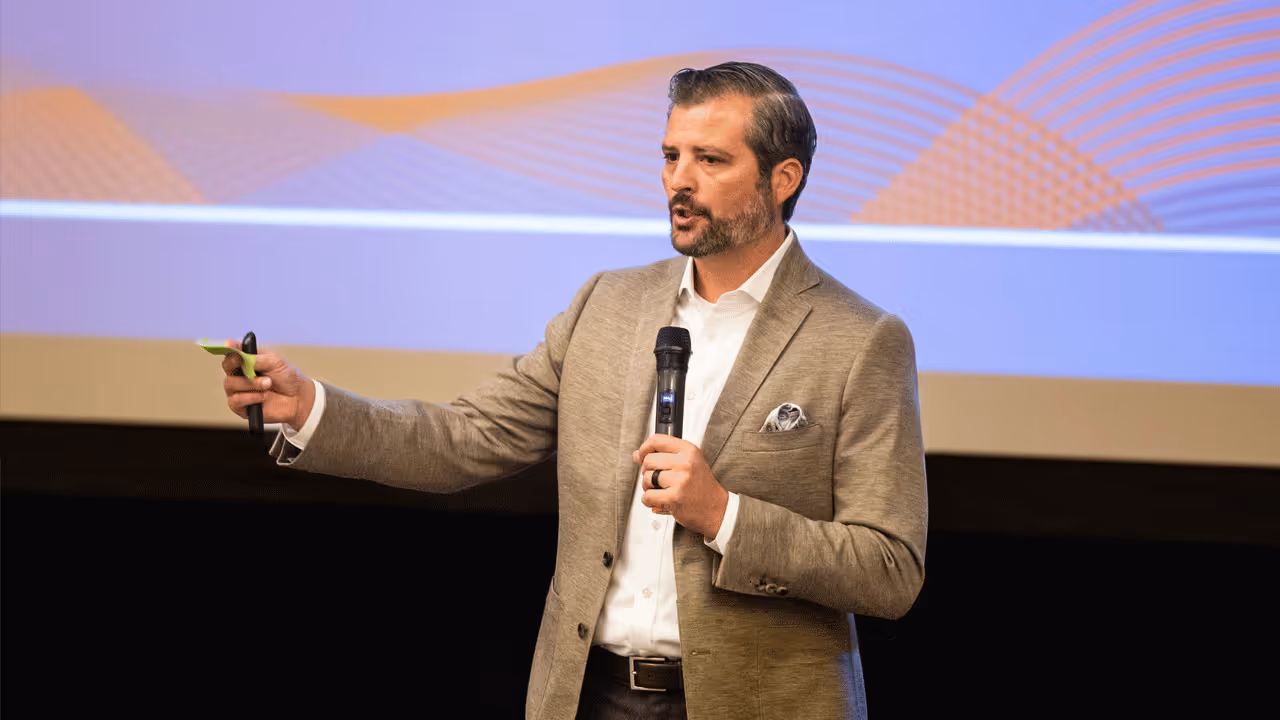 Tria Federal CEO Tim Borchert speaking into a microphone while holding a presentation clicker.