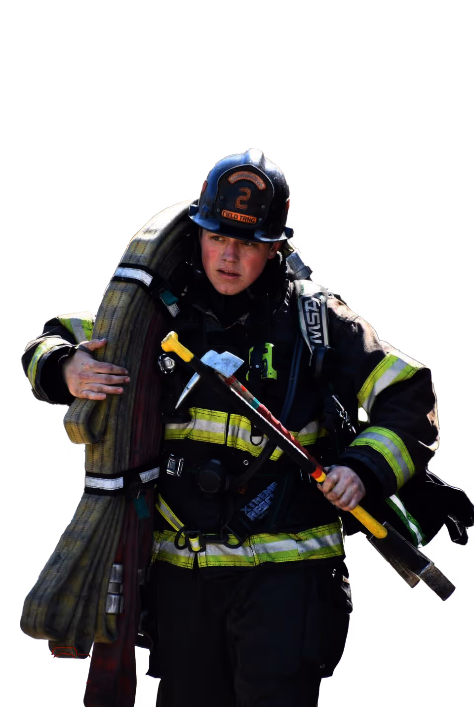 Firefighter wearing full gear and helmet carrying a coiled fire hose over one shoulder and holding a fire axe.