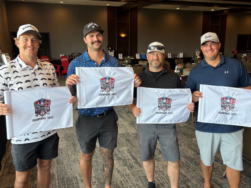 Firefighter wearing full gear and helmet cutting a wooden beam with a power saw, sending sparks flying.