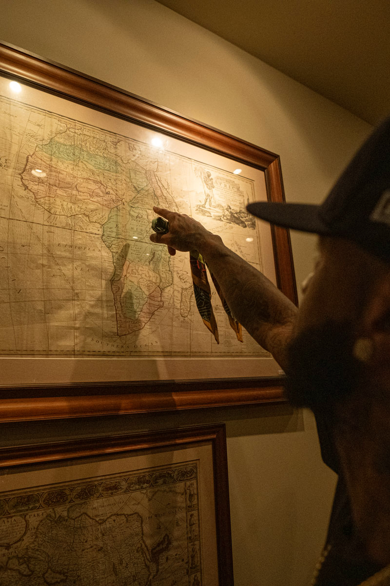 Person wearing a cap points at a framed vintage map of Africa on a wall.