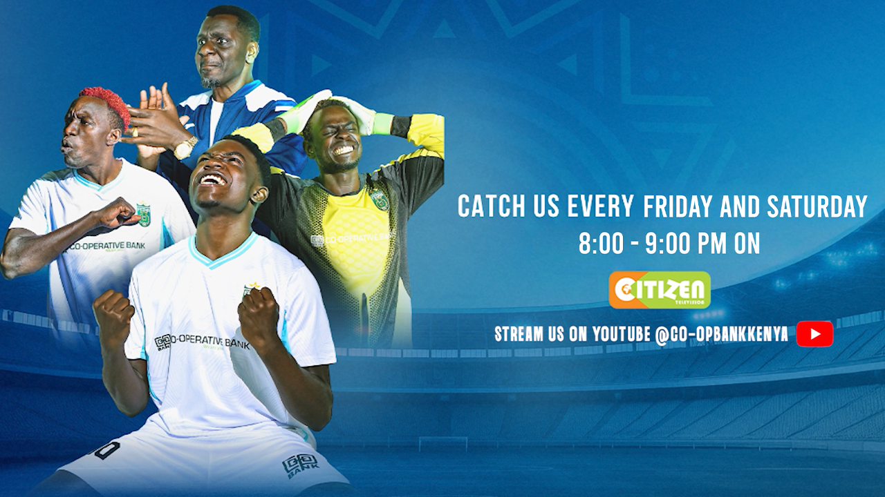 Person in black hoodie and cap holding a script or notebook, directing or speaking, with two people blurred in the background at night.